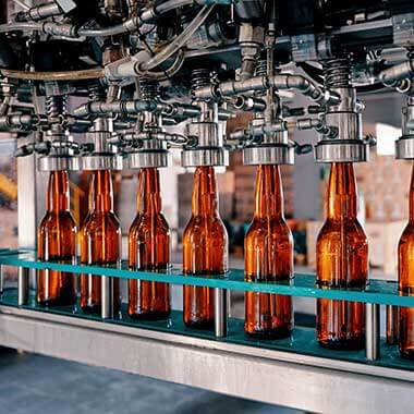 Garrafas de vidro em circulação numa fábrica de bebidas. A monitorização da dureza da água é importante para gerir a qualidade do produto.