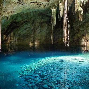 Uma reserva de água de cor turquesa brilha numa gruta. A cor é causada por minerais finamente moídos suspensos na água.